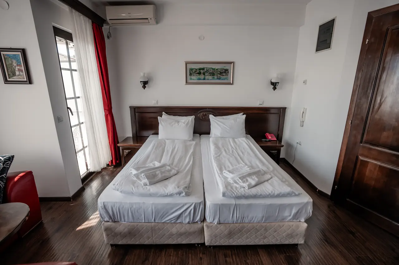 Twin beds made up as a double, red curtains, balcony doors