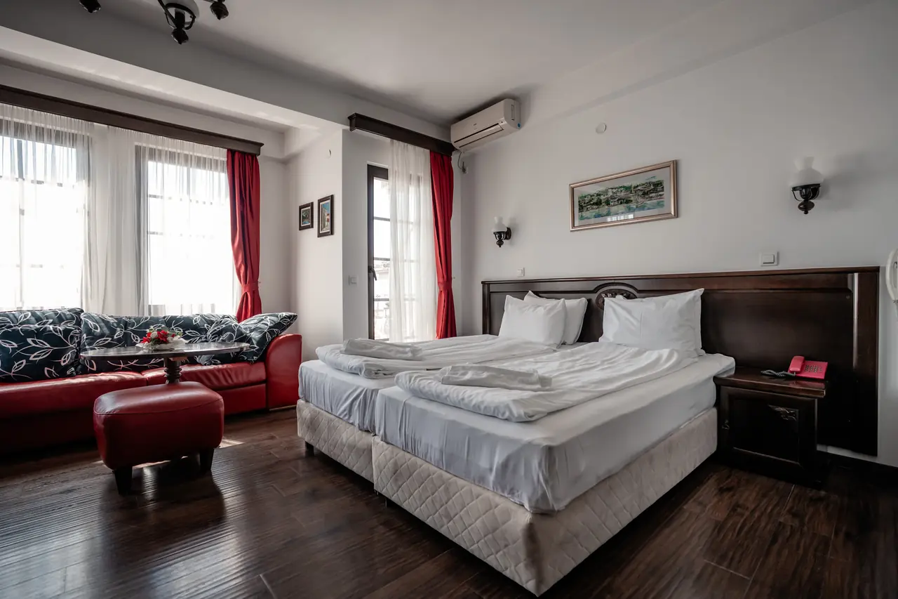Wide: red sofa and ottoman by the windows, beds on the right