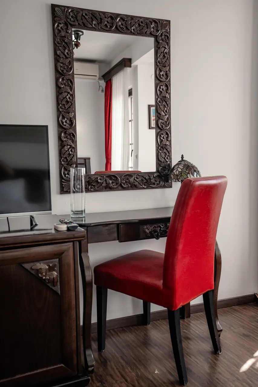 Desk with carved mirror and red chair, portrait