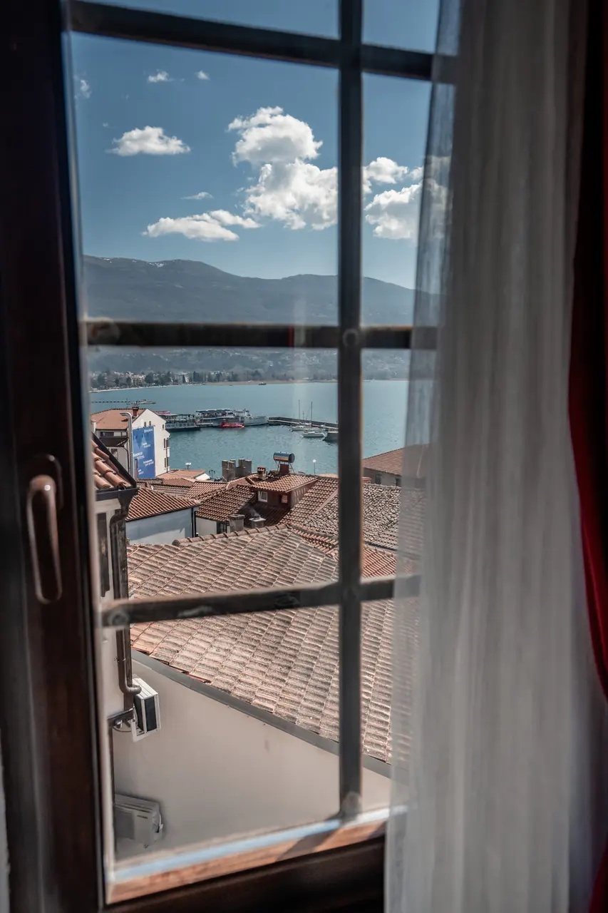 Through the balcony door: lake and old-town roofs, portrait