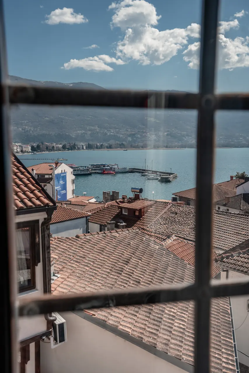 Window view over roofs to the lake, clouds, portrait
