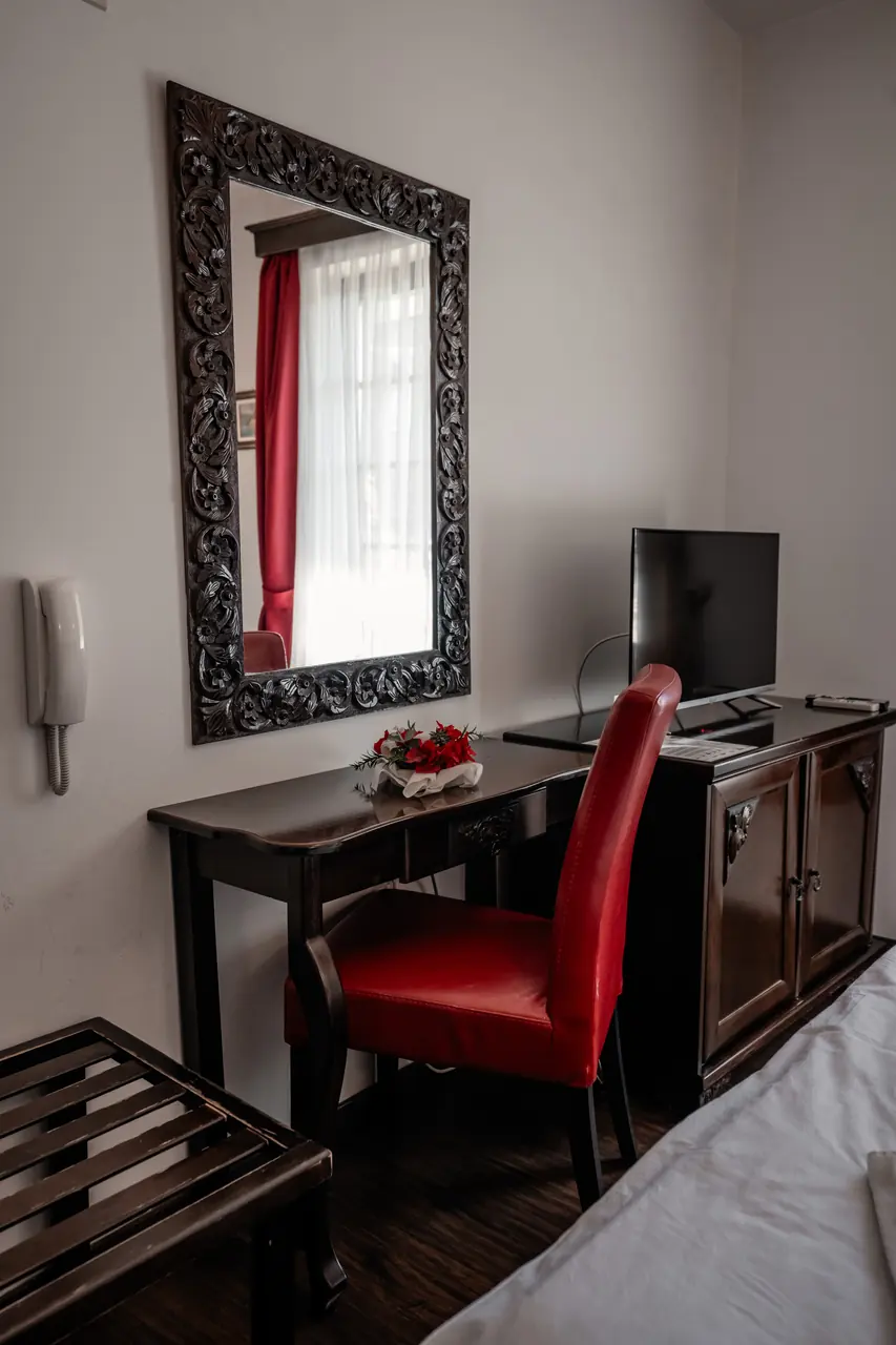 Desk with red chair and carved mirror, portrait