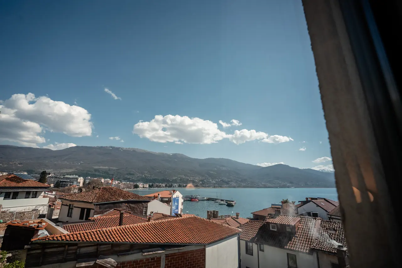 Window view over roofs to the lake, clouds