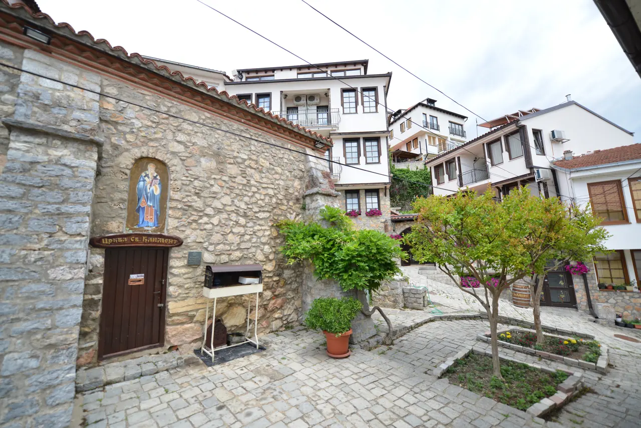 The small stone church of St. Kliment with an icon over its door, beside the villa