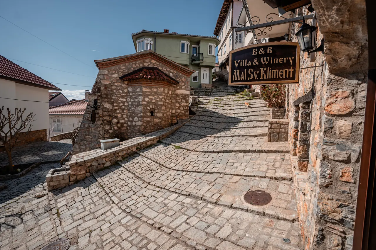 The cobbled lane with the little stone church of St. Kliment and the villa's hanging sign