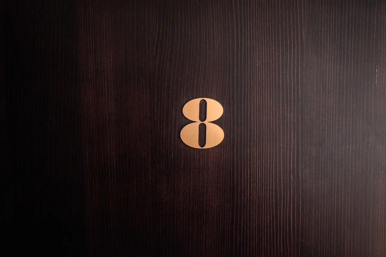 Brass room number 8 on dark wood door
