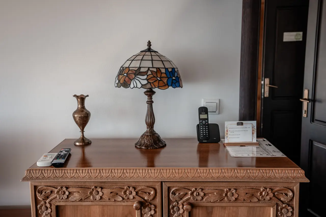 Carved walnut dresser with Tiffany lamp and brass vase
