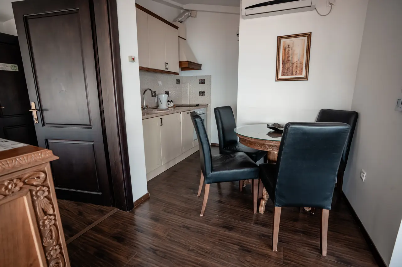 Dining corner with black chairs, kitchenette and carved cabinet